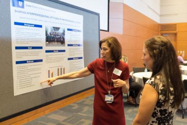 two faculty examining a research poster